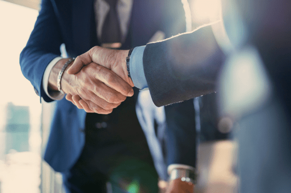 Two business men shake hands after agreeing to terms on office equipment.