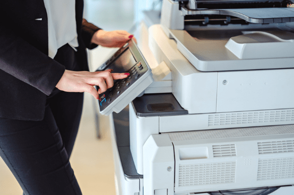 Close up image of a professional woman using a multifunction system printer in an office