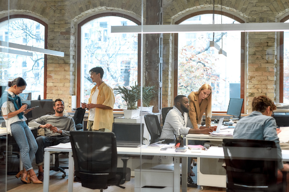 Busy modern office with young professionals working surrounded by office equipment.