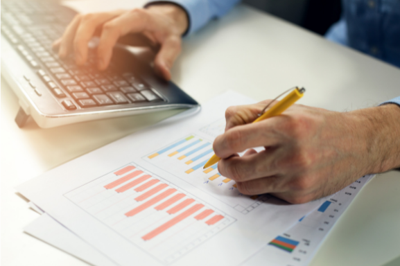 Close up of a businessman assessing colorful charts on a page while typing in data on a keyboard signifying the importance of data capture