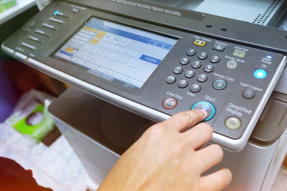 Close up of a worker standing at an office multifunction printer using the interface.
