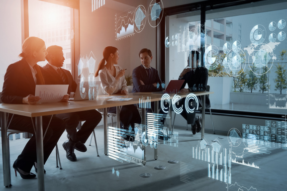 A team of IT professionals sit around a table discussing their clients' network security updates as a cybersecurity services company.
